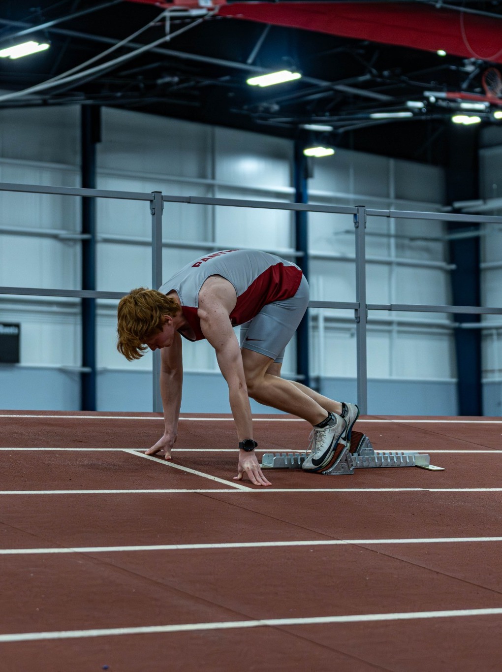 Alex Moynihan setting up in starting blocks during collegiate sprint training.